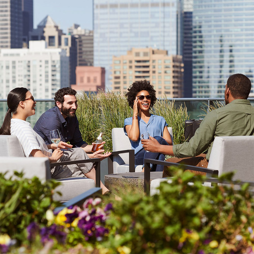 4 people enjoy drinks at an outdoor lounge space
