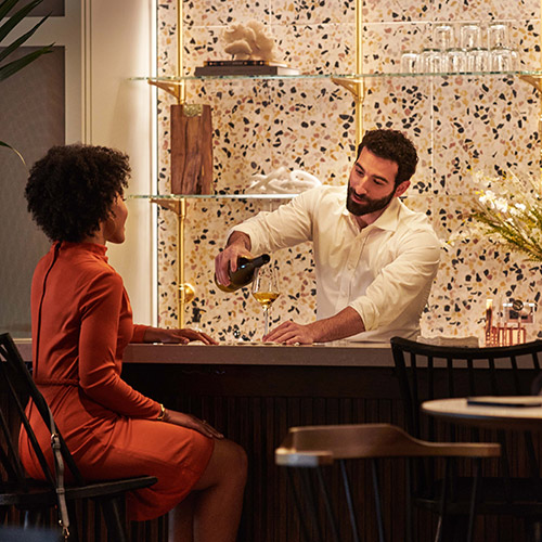 A bartender pours a woman a glass of white wine